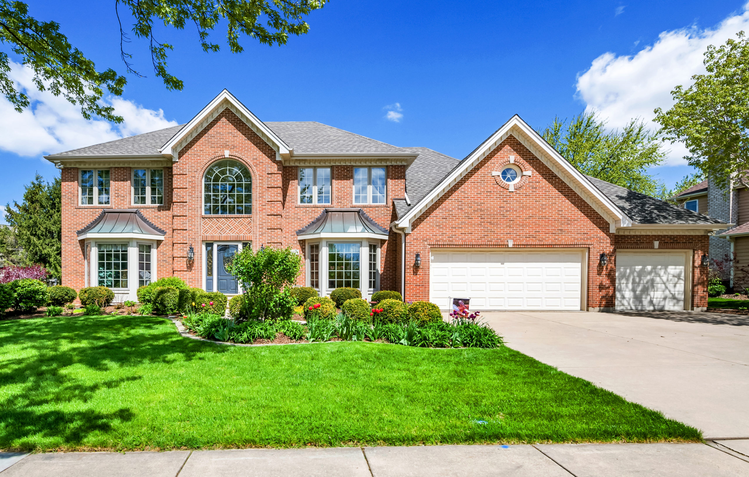 A serene suburban home with a well-maintained lawn under a clear blue sky.